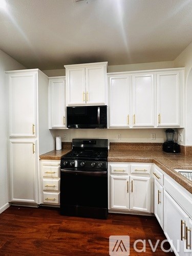 A kitchen with white cabinets and a black stove top oven.