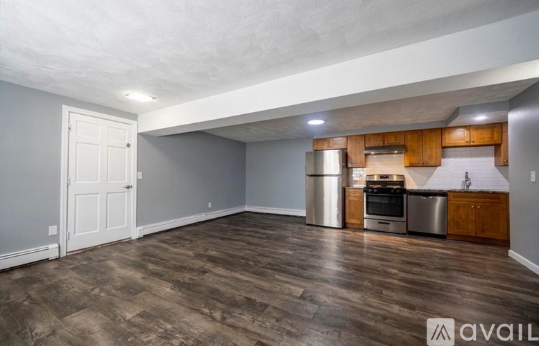 A kitchen area with wooden cabinets and a stainless steel refrigerator.