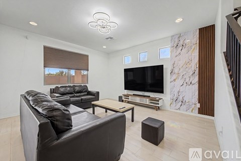 A living room with a black couch and a television.