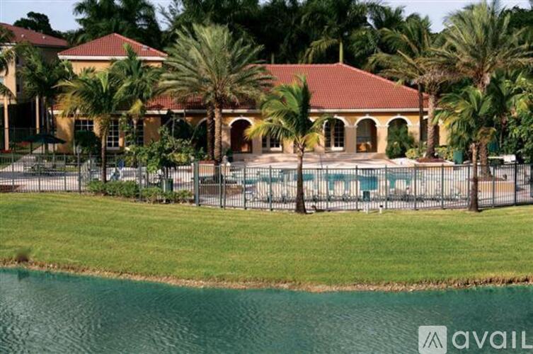 A house with a pool and palm trees in front.