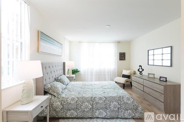 A bedroom with a bed, nightstand, and a window with curtains.