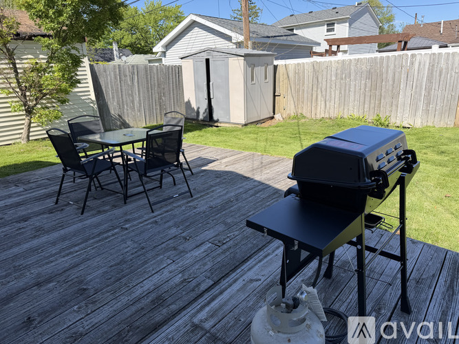A BBQ grill is on a wooden deck with a table and chairs.