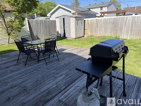 A BBQ grill is on a wooden deck with a table and chairs.