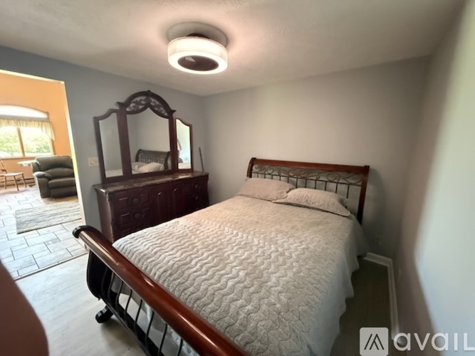 A bedroom with a bed, a mirror, and a dresser.