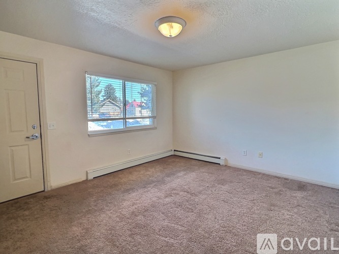 A room with a carpeted floor and a window showing a house and trees outside.