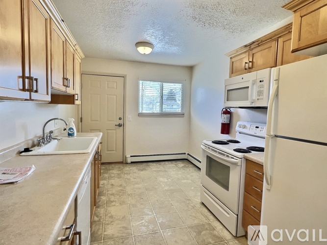 A kitchen with a white refrigerator, sink, and cabinets.