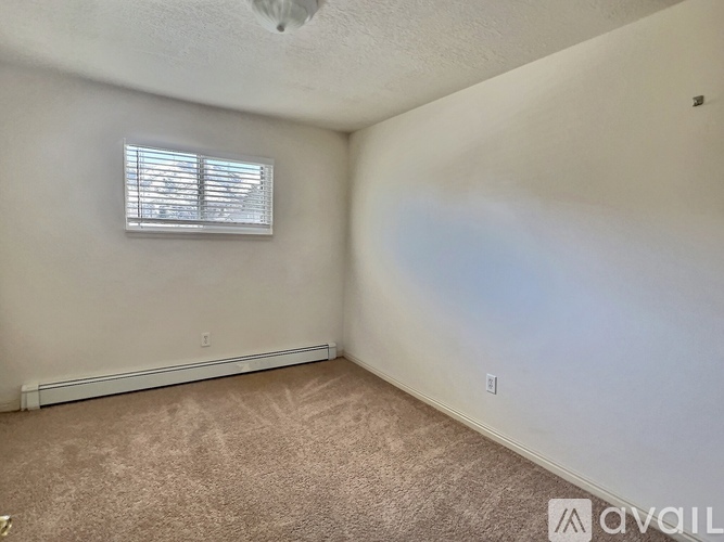 A room with a carpeted floor and a window with blinds.