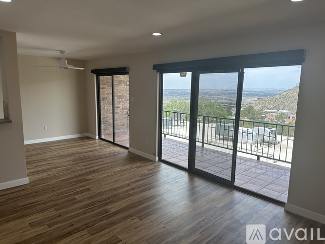 A spacious room with wooden floors and sliding glass doors that open to a scenic view.