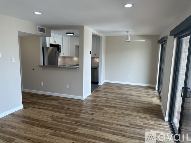 A spacious room with wooden flooring and a kitchen area with a stove and cabinets.