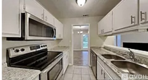 A kitchen with white cabinets and black appliances.