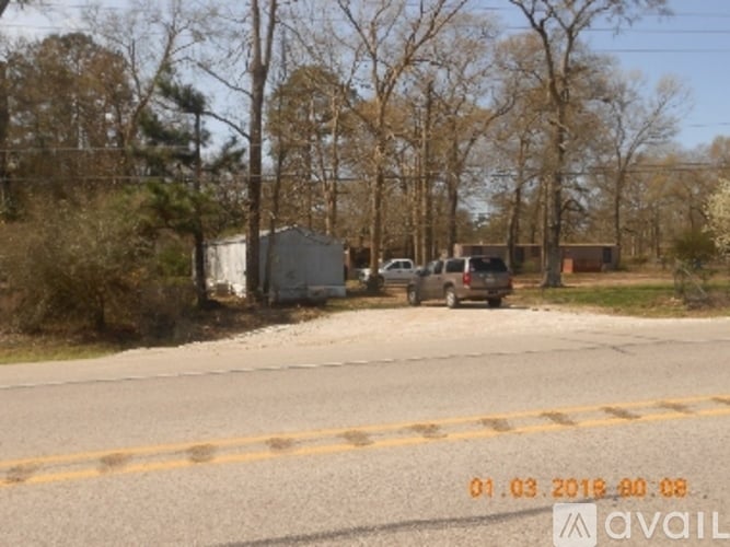 A car is parked on the side of a road with trees in the background.