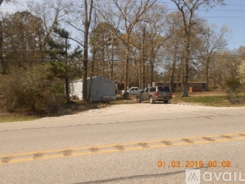 A car is parked on the side of a road with trees in the background.