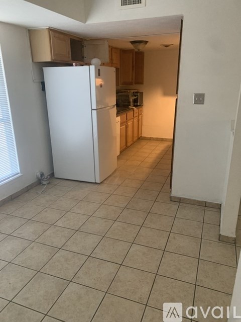 A kitchen with a white refrigerator and white tiled floor.