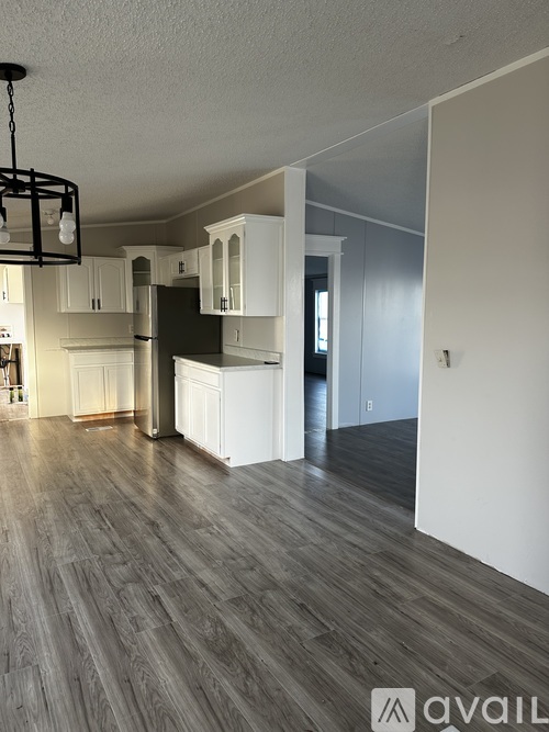 A kitchen with white cabinets and a black fridge is shown.