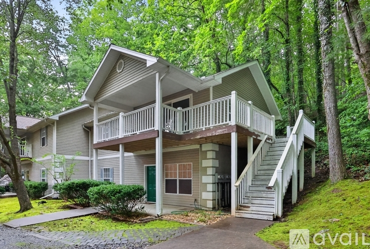 A house with a green door and a balcony is surrounded by trees.