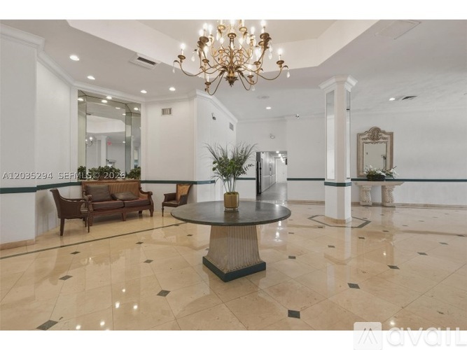 A chandelier hangs over a table in a spacious room with a marble floor.