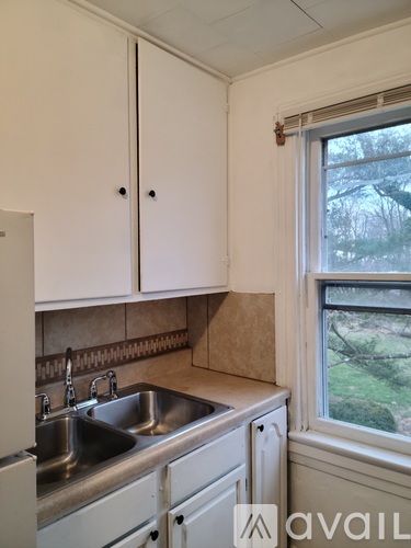 A kitchen with white cabinets and a window.