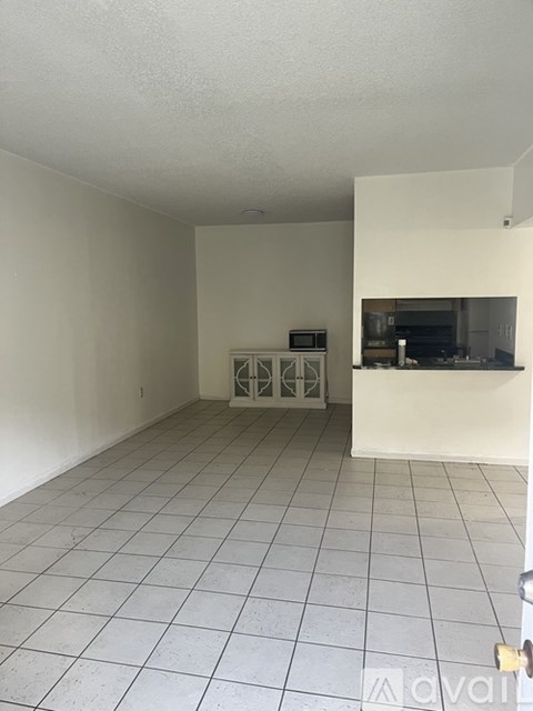A white tiled room with a microwave and oven in the kitchen area.