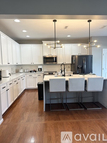 A modern kitchen with white cabinets and a wooden floor.