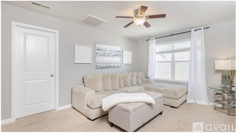 A living room with a white couch and a ceiling fan.