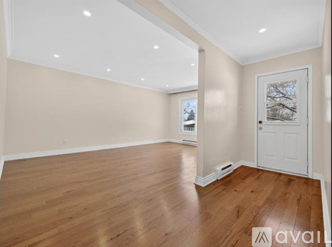 A spacious room with wooden flooring and a white door.