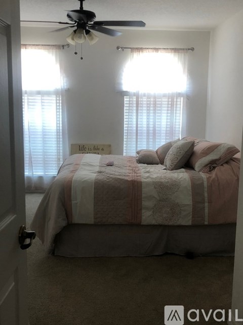 A bedroom with a bed and a ceiling fan.