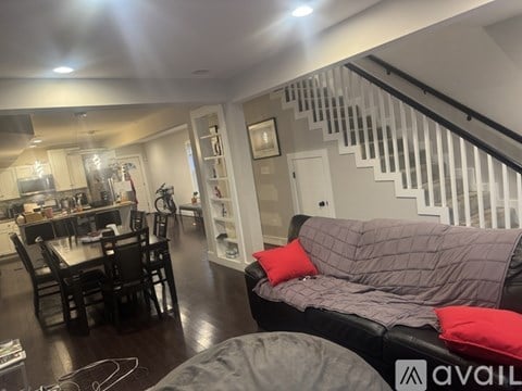 A living room with a grey couch and a dining table with chairs.