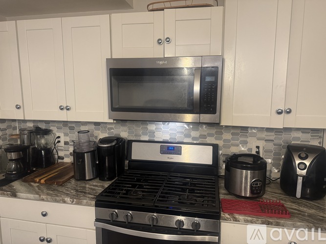 A kitchen with a black stove top oven and a silver microwave above it.