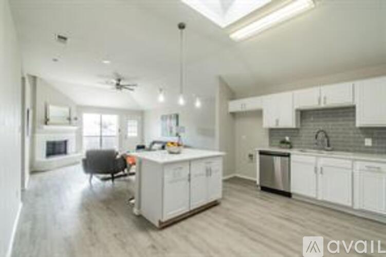 A modern kitchen with white cabinets and a wooden floor.