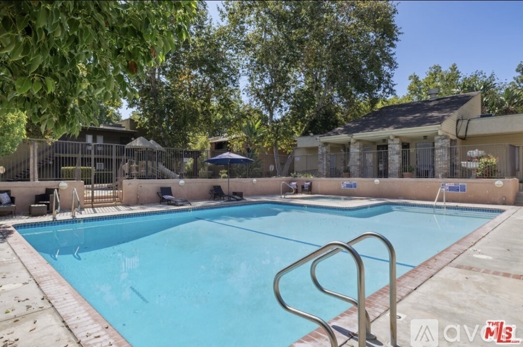 A large swimming pool with a diving board and a metal ladder.
