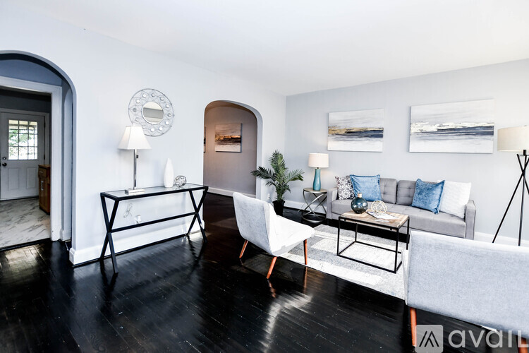 A living room with a white couch, a black coffee table, and a white chair.