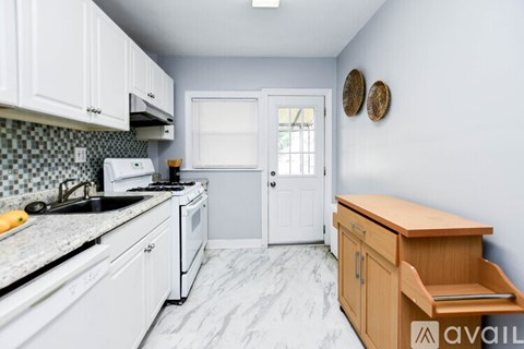 A kitchen with white cabinets and a marble countertop.