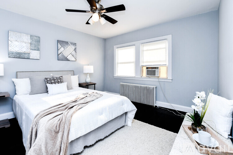 A bedroom with a bed, a ceiling fan, and a window.