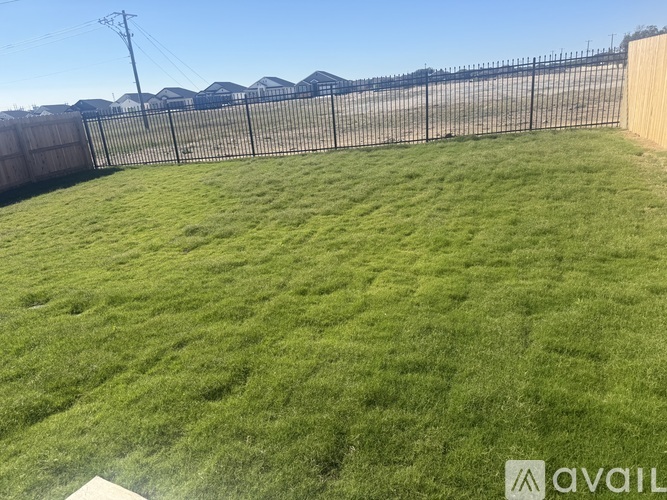 A backyard with a fence and a grassy area.
