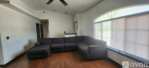 A living room with a grey sectional sofa and a wooden floor.