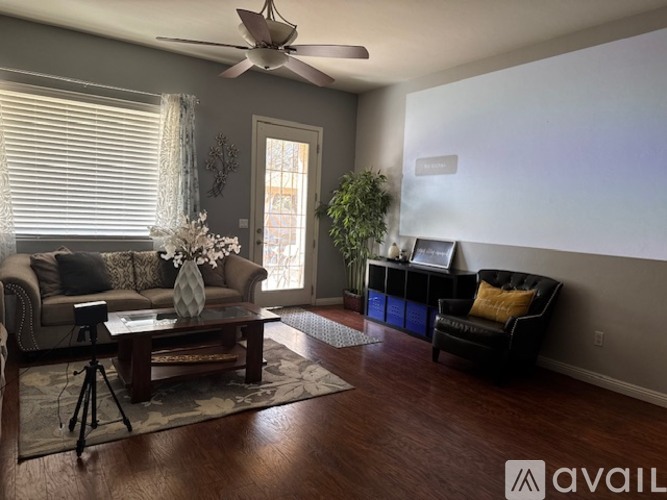 A living room with a black couch, a wooden coffee table, and a ceiling fan.
