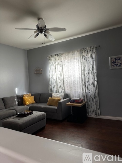 A living room with a grey couch and a ceiling fan.