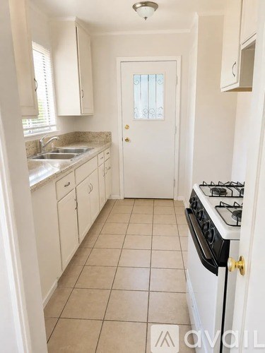 A white kitchen with a stove and sink.