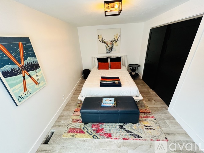 A bedroom with a bed, a rug, and a painting on the wall.
