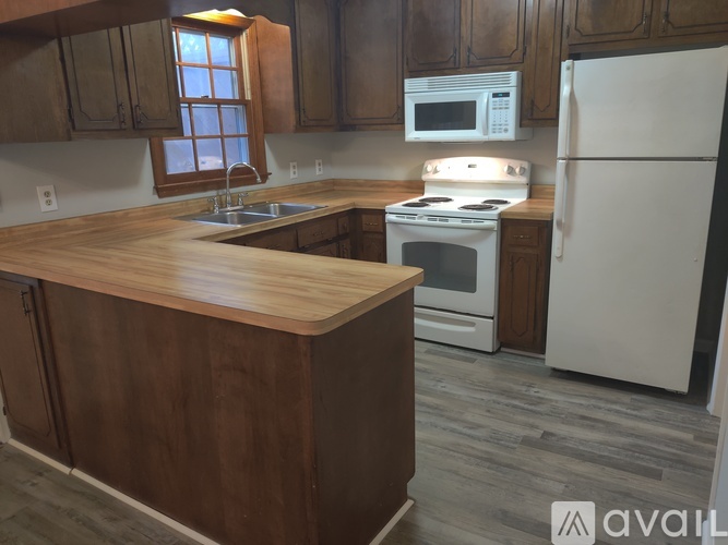 A kitchen with a wooden island and white appliances.