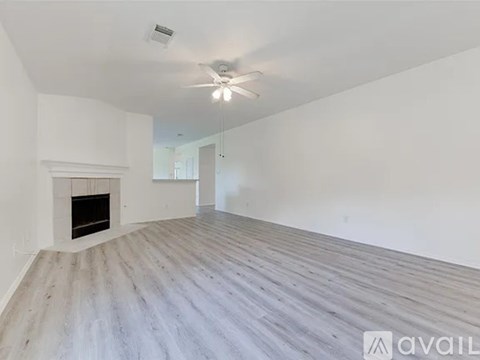 A spacious room with a fireplace and wooden flooring.