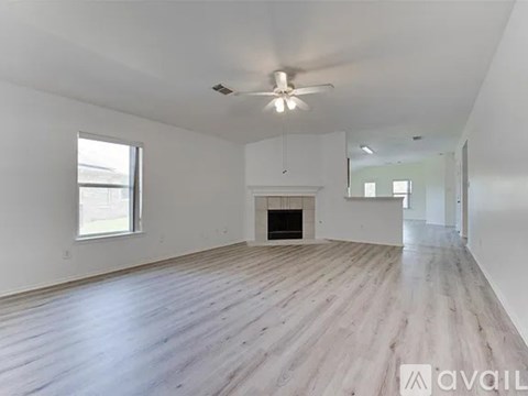 A spacious room with wooden flooring and a fireplace.