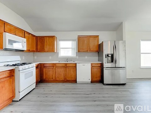 A kitchen with wooden cabinets and stainless steel appliances is available for rent.