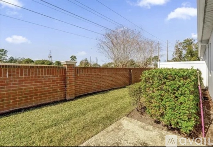 A backyard with a brick wall and green grass.