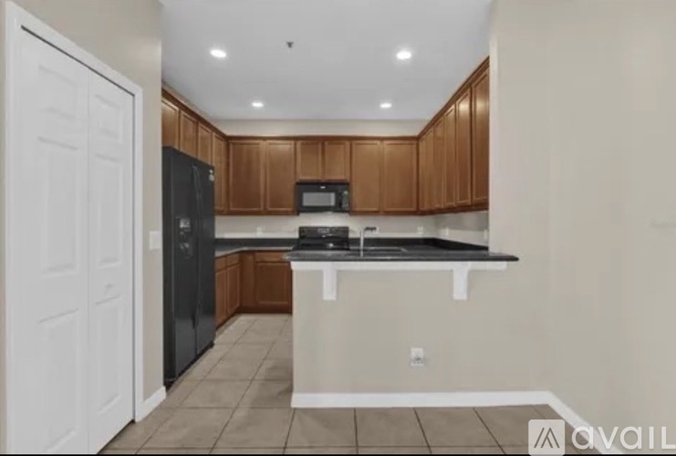 A kitchen with brown cabinets and black appliances.