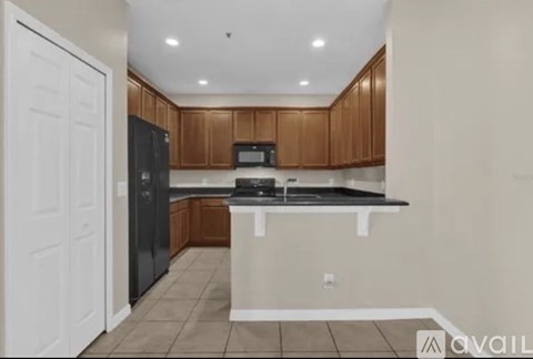 A kitchen with brown cabinets and black appliances.