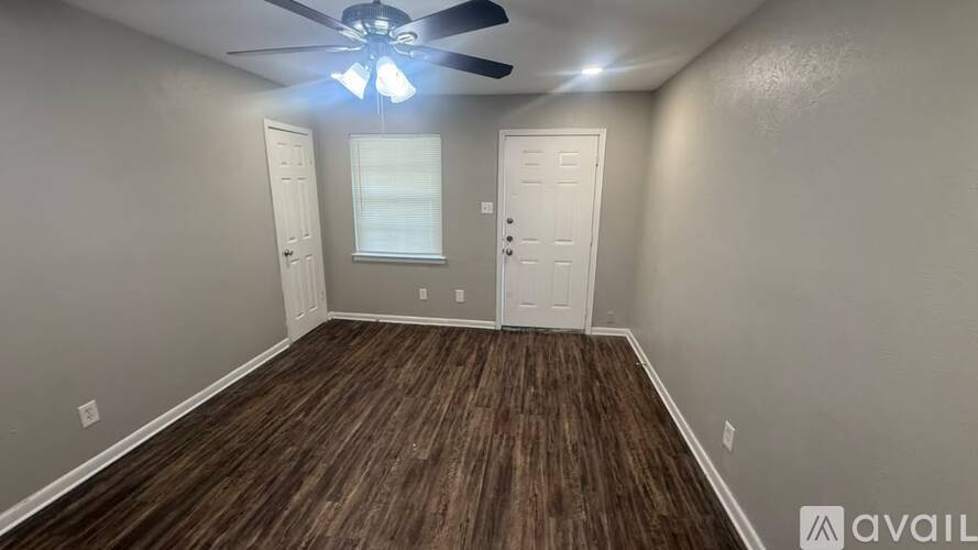 A room with a ceiling fan and wooden flooring.