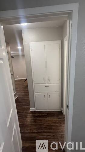 A hallway with a white door and a wooden floor.