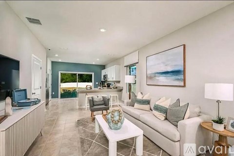 A living room with a white couch, a coffee table, and a painting on the wall.