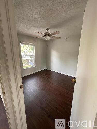 A room with a ceiling fan and wooden floors.